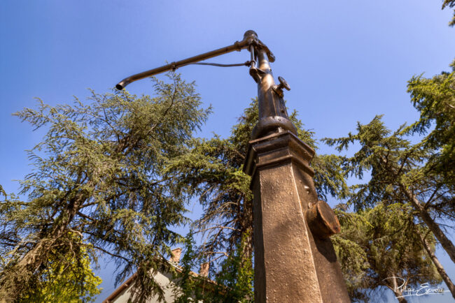 Ancienne pompe à eau de gare en métal sous un ciel bleu