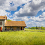 Vue large d’une gare fantôme en ruine avec prairie au premier plan