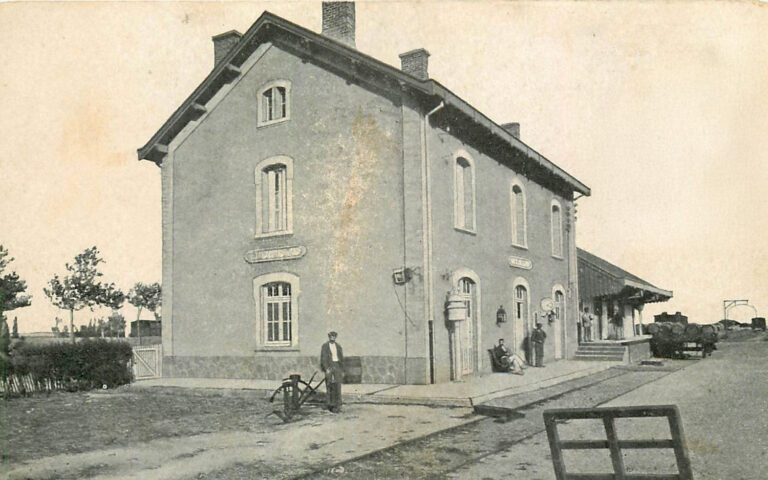 Carte postale ancienne en noir et blanc représentant une gare avec voyageurs sur le quai