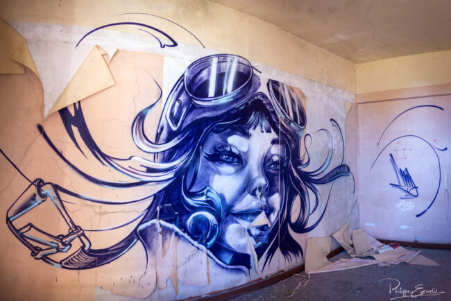 Fresque murale représentant une femme pilote peinte dans une gare abandonnée