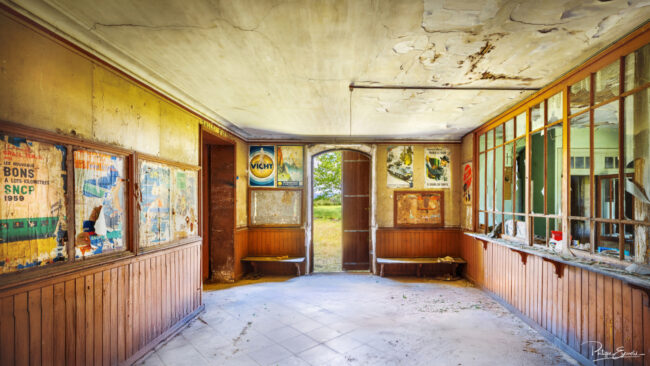 Hall intérieur d’une gare abandonnée aux murs tapissés d’affiches rétro SNCF