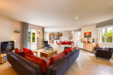 Grand salon moderne avec cuisine ouverte, canapé gris et table à manger conviviale