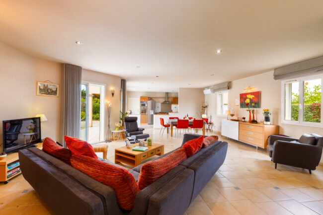 Focus sur Rémi Alba, Conciergerie "OC Keys" 4 Grand salon moderne avec cuisine ouverte, canapé gris et table à manger conviviale