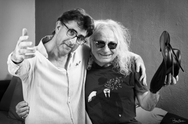 Portrait en noir et blanc de deux amis complices se tenant par les épaules et souriant à l’objectif, ambiance chaleureuse et amicale.