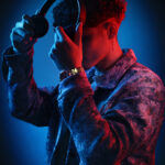 Jeune homme ajustant un casque audio sous une lumière studio rouge et bleue