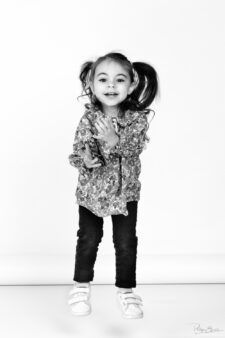 Portrait en noir et blanc d’une petite fille avec des couettes qui bouge en studio photo