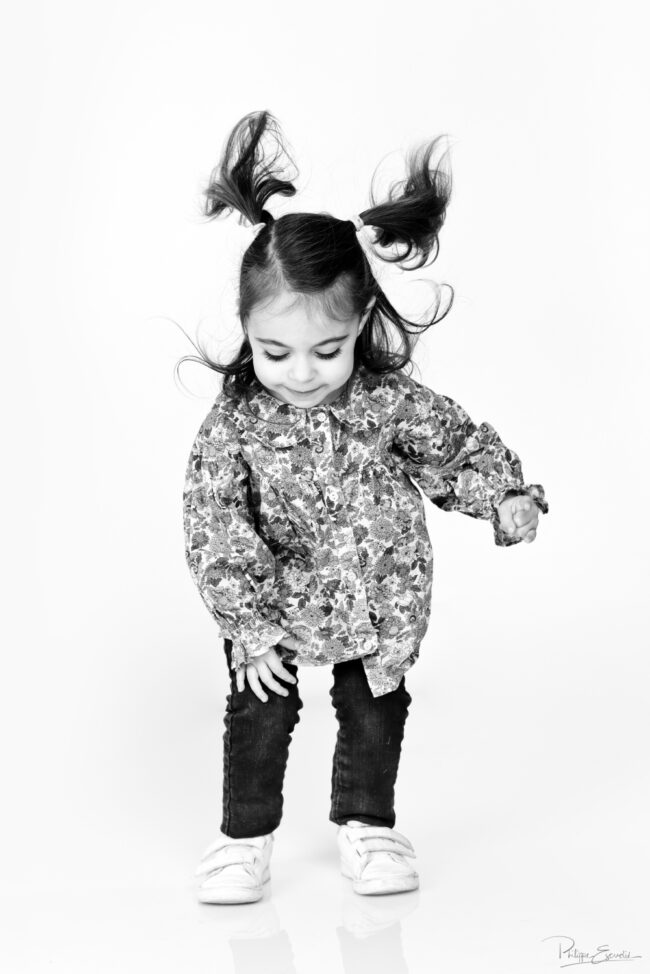 Petite fille souriante en train de sauter sur fond blanc en studio