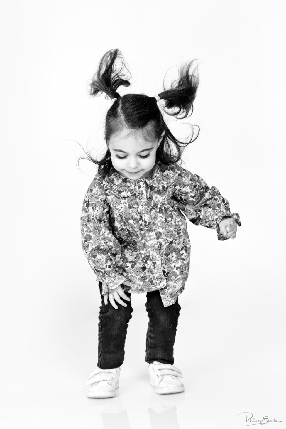 Petite fille souriante en train de sauter sur fond blanc en studio