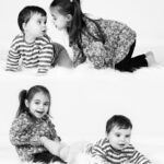 Deux enfants jouant ensemble allongés sur un tapis blanc en studio noir et blanc. On voit deux fois les enfants sur la même image.