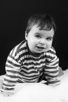 Bébé souriant en noir et blanc sur fond sombre en studio