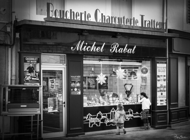 Devanture de boucherie décorée pour Noël, vitrines éclairées et éléments décoratifs visibles en façade.