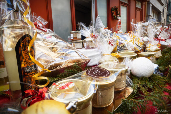 Gros plan sur des produits gourmands emballés, bocaux et bouteilles disposés sur une table décorée pour Noël.