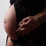 Gros plan sur les mains du futur père posées avec douceur sur le ventre arrondi de la future maman.