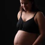 Portrait en low key d’une future maman avec un bola reposant sur le ventre, symbole de la maternité.