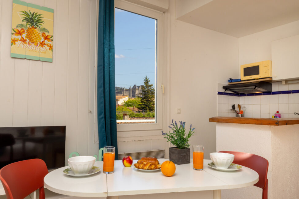 Table dressée avec un petit déjeuner devant une fenêtre avec vue sur la cité médiévale de Carcassonne