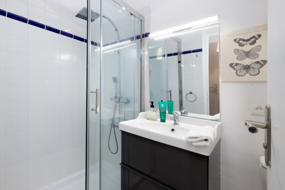 Salle de bain moderne avec douche vitrée, miroir éclairé et meuble avec vasque