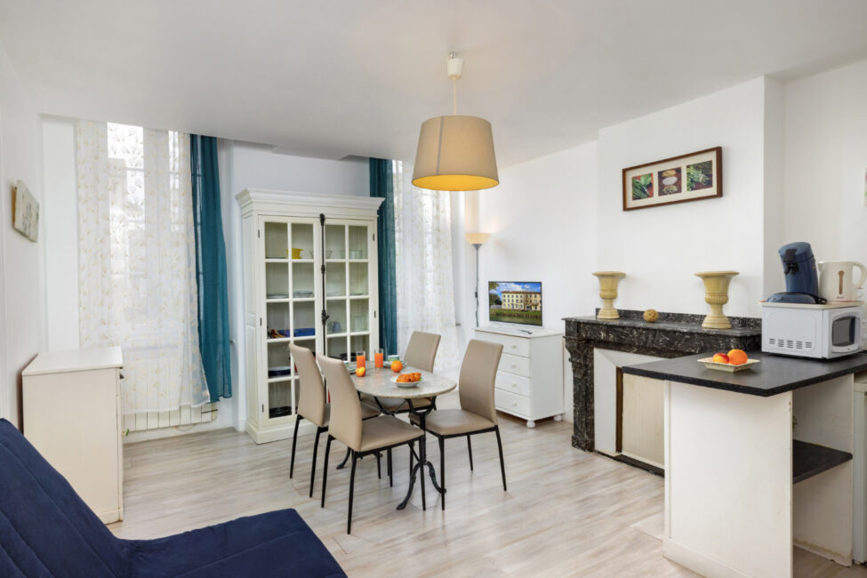 Pièce de vie lumineuse avec espace repas, cuisine ouverte et mobilier contemporain dans un appartement de location courte durée