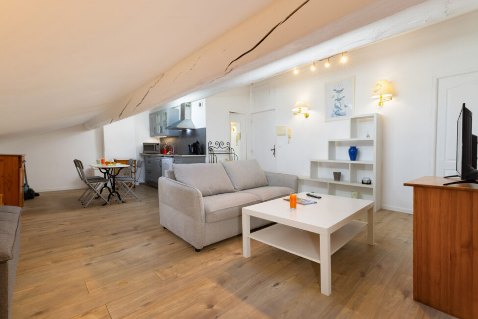 Pièce de vie aménagée sous pente avec salon, coin repas et cuisine ouverte