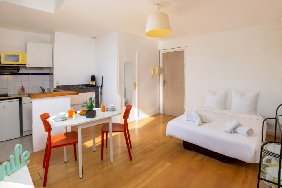 Studio équipé avec lit double, kitchenette ouverte et espace repas baigné de lumière naturelle