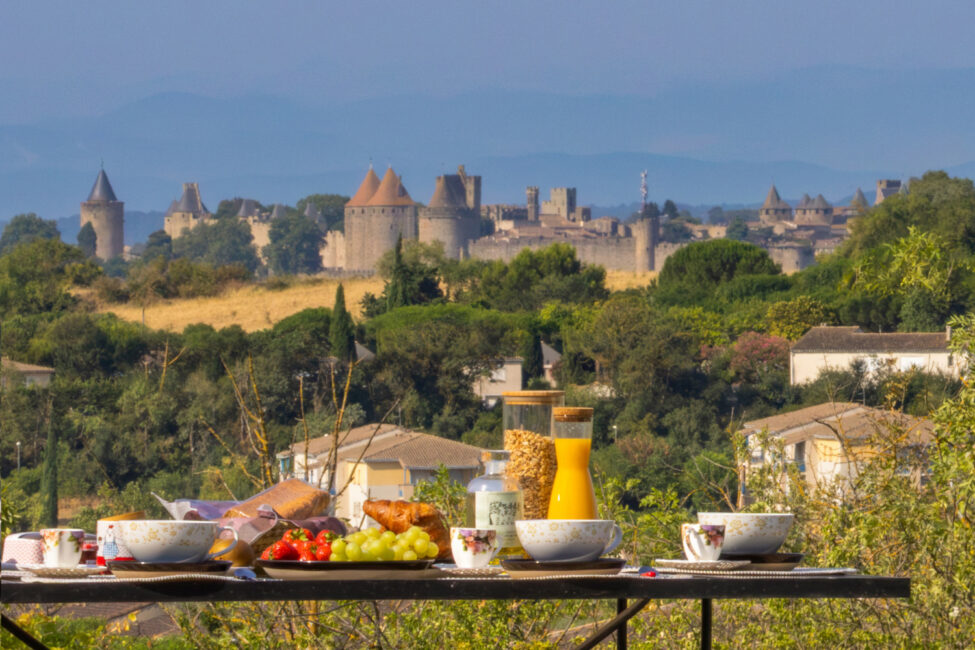 Photographe immobilier à Carcassonne : quand un shooting professionnel change tout 3 able dressée pour le petit-déjeuner avec la Cité de Carcassonne en arrière-plan.