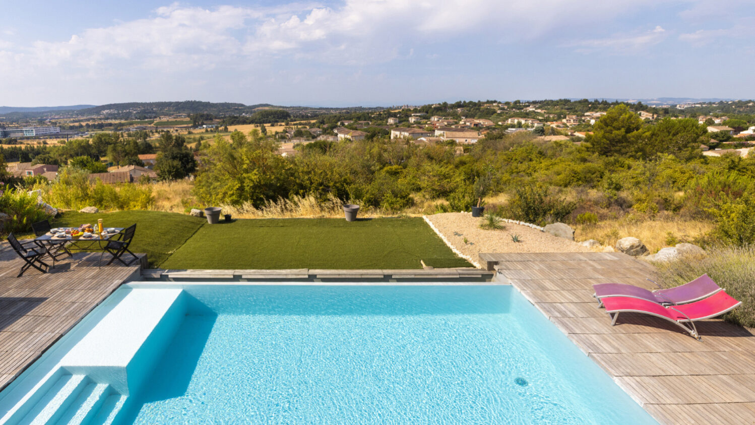 Piscine contemporaine avec terrasse et vue dégagée sur les collines environnantes.