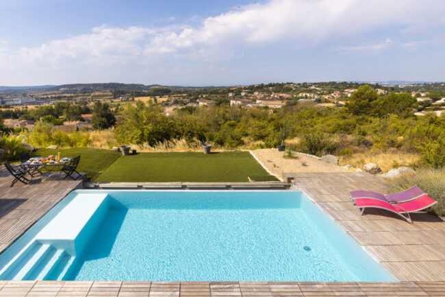 Piscine contemporaine avec terrasse et vue dégagée sur les collines environnantes.