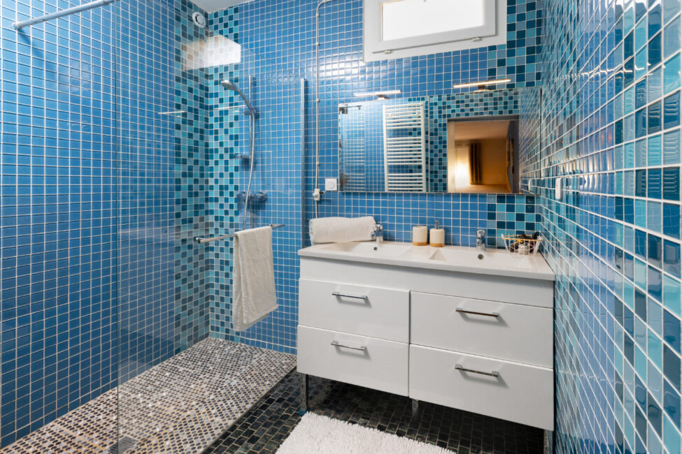 Photographe immobilier à Carcassonne : quand un shooting professionnel change tout 10 Salle de bains avec douche à l'italienne, double vasque et faïence bleue.