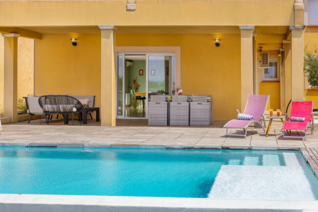 Terrasse couverte avec salon de jardin donnant sur la piscine.