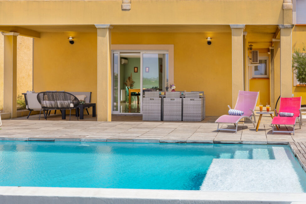 Photographe immobilier à Carcassonne : quand un shooting professionnel change tout 5 Terrasse couverte avec salon de jardin donnant sur la piscine.