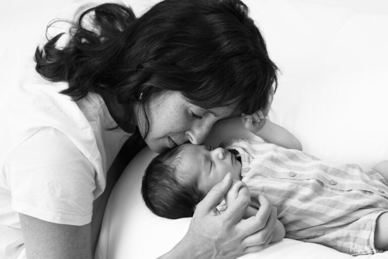 Photo noir et blanc d'une maman embrassant tendrement son nouveau-né pendant une séance photo bébé à Carcassonne