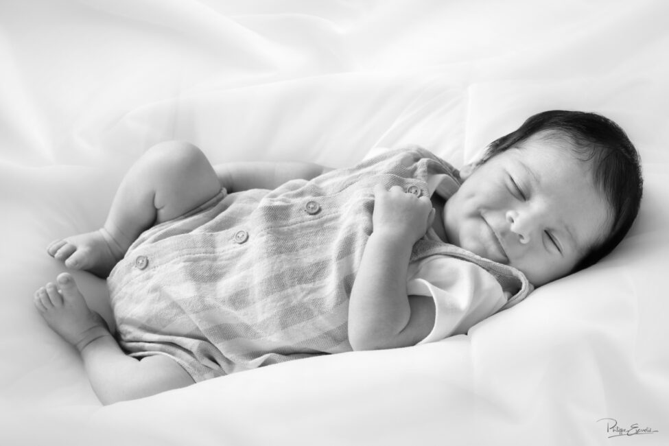 Portrait naturel en noir et blanc d’un nouveau-né allongé et souriant