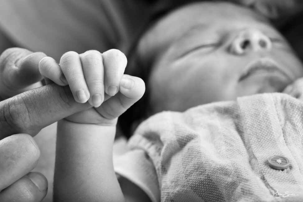 Gros plan sur la petite main d’un bébé tenant le doigt de son parent
