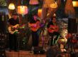 Groupe de musique live se produisant sur une petite estrade en bois pendant une soirée en extérieur.