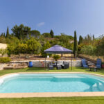 Piscine extérieure entourée d’un jardin aménagé avec salon sous tonnelle, transats, végétation méditerranéenne et espaces de détente.