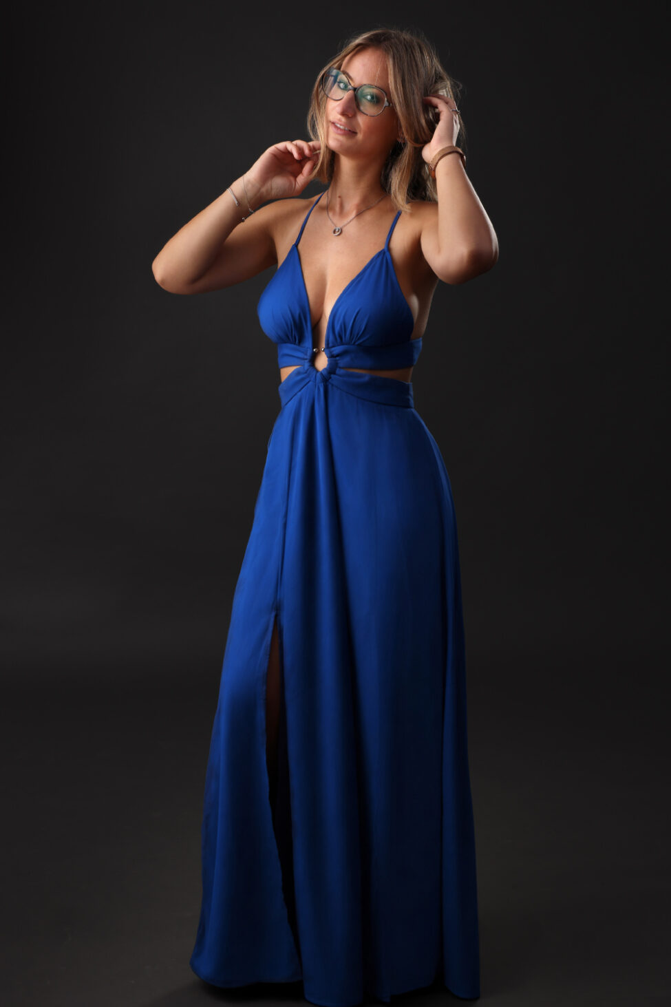 Portrait studio en pied d’une femme en longue robe bleue sur fond sombre