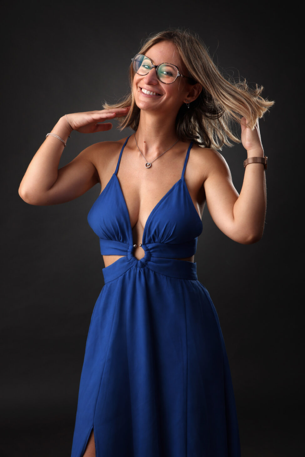 Portrait en studio d’une femme souriante en robe bleue sur fond sombre