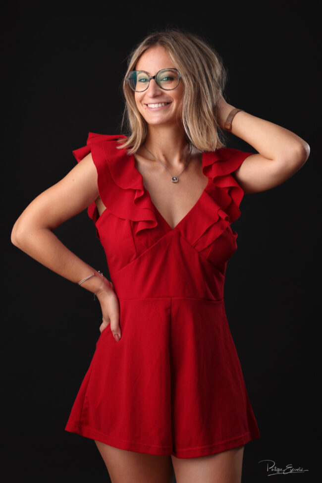 Portrait mode d’une femme souriante en tenue rouge sur fond noir