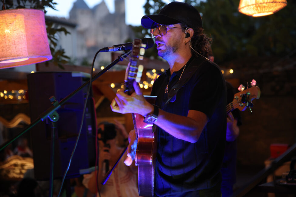 Les Noy’s et le Coco Bongo au cœur de la Féria de Carcassonne 8 Guitariste chanteur photographié sur scène pendant un concert avec la cité de Carcassonne en arrière plan.