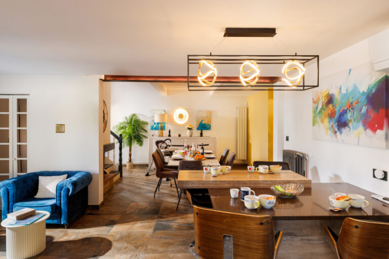Vue d'ensemble d'un intérieur contemporain associant cuisine avec comptoir, espace repas et décoration colorée, dans une atmosphère chaleureuse.